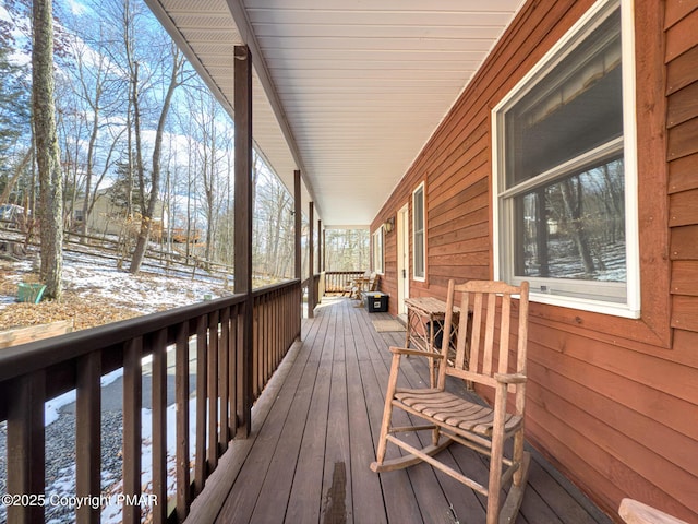 snow covered deck featuring covered porch