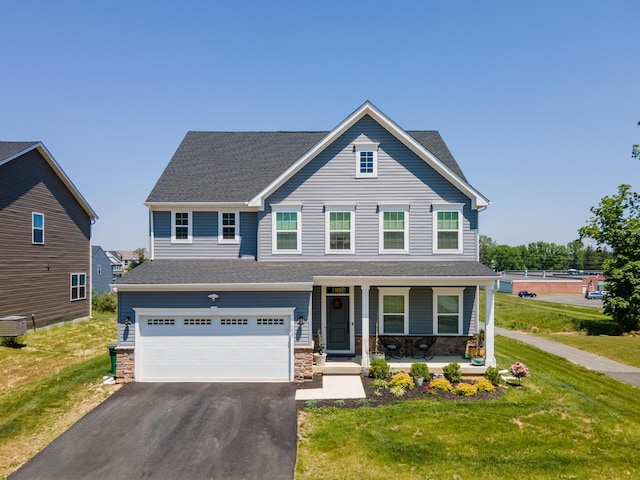 view of front of property featuring covered porch, driveway, a garage, a front lawn, and stone siding