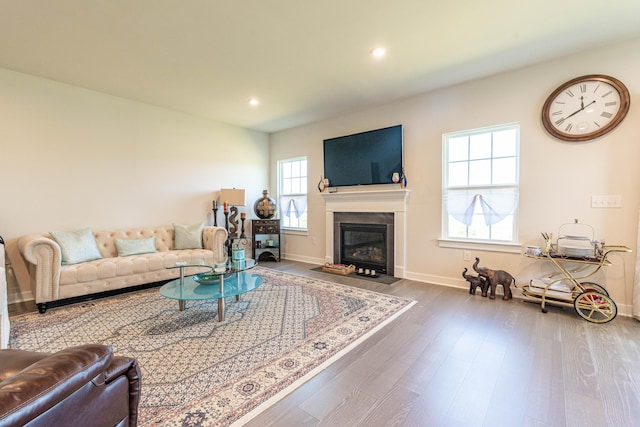 living room featuring wood finished floors, baseboards, recessed lighting, and a fireplace with flush hearth