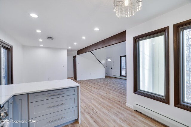 interior space featuring light wood finished floors, light stone counters, baseboard heating, gray cabinetry, and recessed lighting