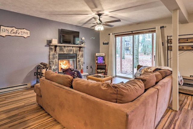 54 Spencer Ln, Albrightsville, PA 18210 - living area featuring baseboard heating, a stone fireplace, wood finished floors, and ceiling fan