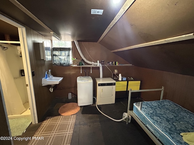 bathroom featuring lofted ceiling, wood walls, a sink, washer and dryer, and a shower stall