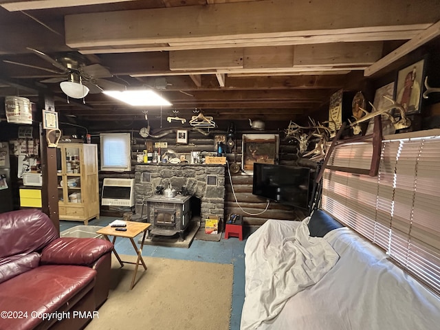 living room featuring a wood stove, heating unit, ceiling fan, and concrete floors