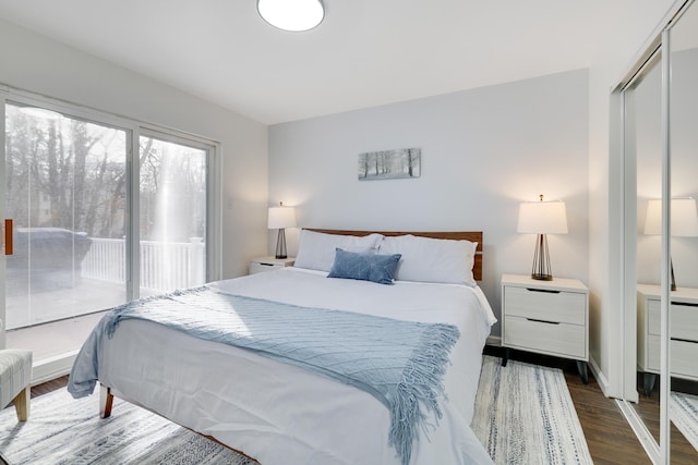 bedroom with dark wood finished floors, access to outside, and a closet