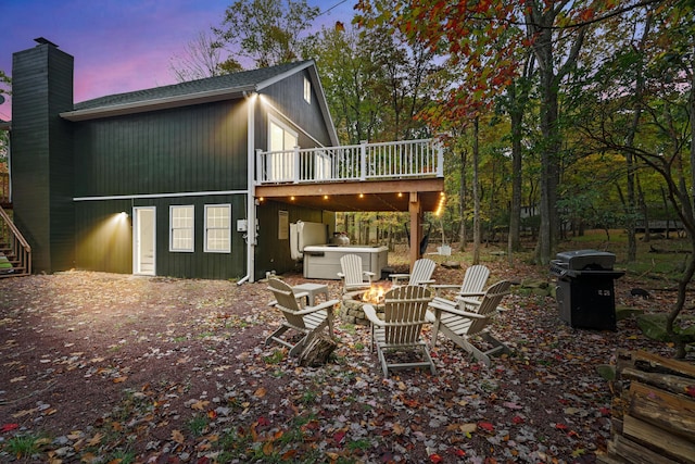 back of house featuring stairs, a fire pit, a chimney, and a wooden deck