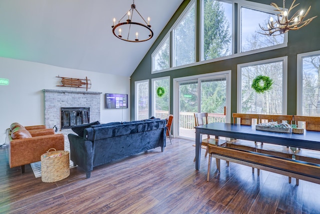 dining room with a notable chandelier, a fireplace, high vaulted ceiling, and wood finished floors