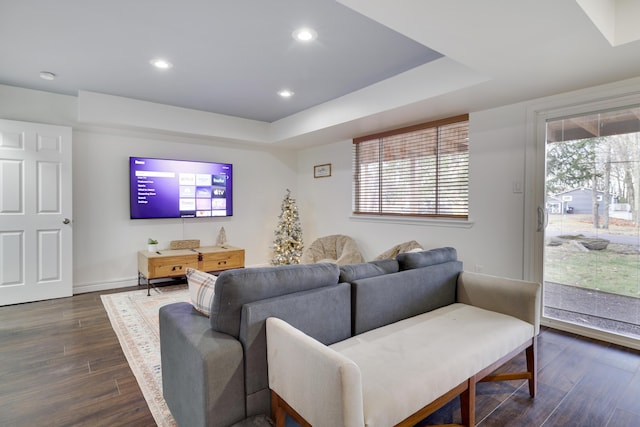 living room with dark wood-style floors, recessed lighting, baseboards, and a tray ceiling