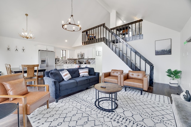 living area with a notable chandelier, high vaulted ceiling, stairway, light wood-style floors, and baseboards