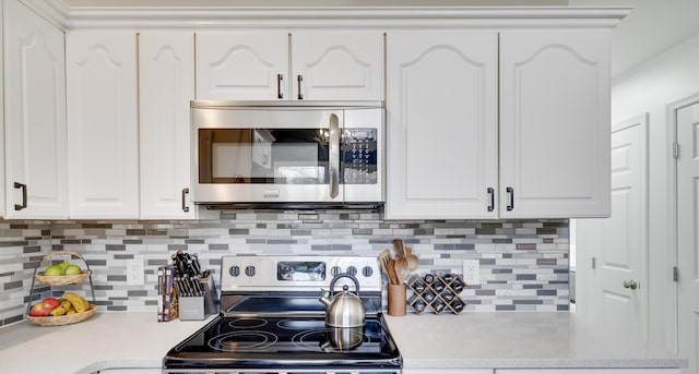 kitchen featuring tasteful backsplash, white cabinetry, stainless steel appliances, and light countertops