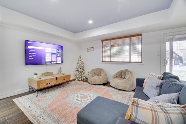 living room with recessed lighting, a tray ceiling, baseboards, and wood finished floors