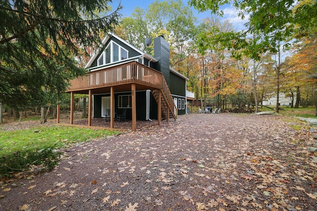 back of property featuring stairway, a chimney, and a deck