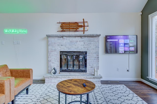 living area featuring wood finished floors, visible vents, baseboards, plenty of natural light, and a fireplace