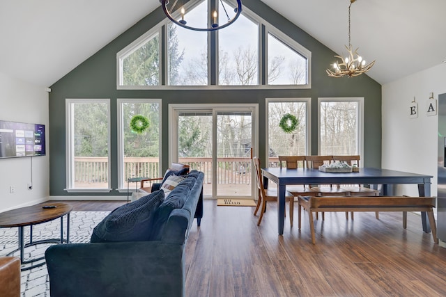 dining area with a wealth of natural light, high vaulted ceiling, an inviting chandelier, and wood finished floors