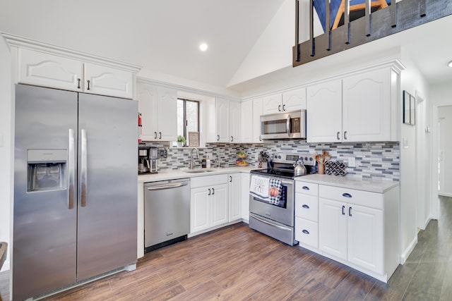 kitchen featuring dark wood-type flooring, light countertops, appliances with stainless steel finishes, white cabinets, and a sink