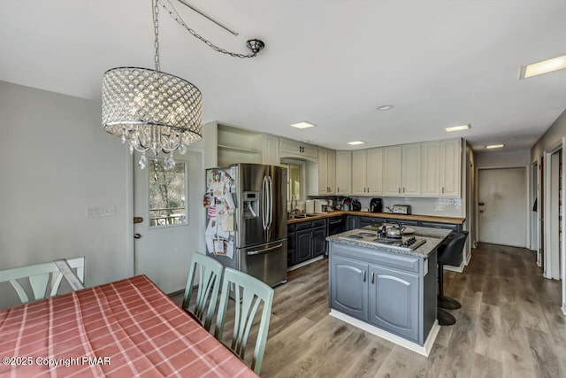 kitchen featuring stainless steel appliances, a kitchen island, an inviting chandelier, and light wood-type flooring