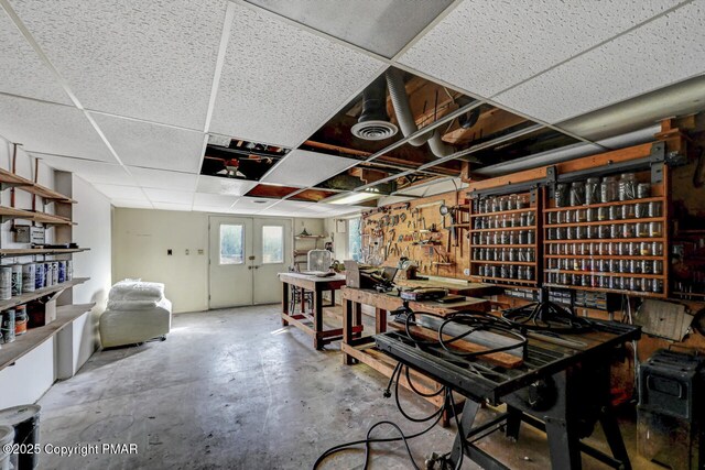 dining area with a paneled ceiling, concrete flooring, and a workshop area