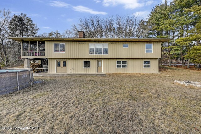 back of house with a patio area, a sunroom, and a lawn