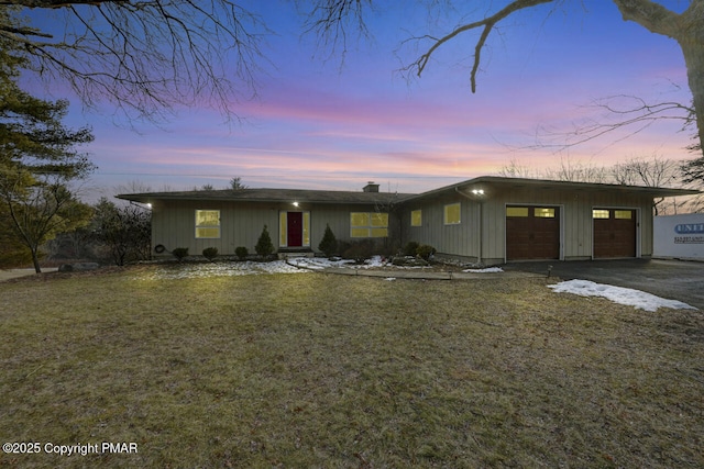 ranch-style home featuring a garage and a yard