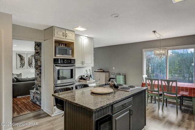 kitchen featuring decorative light fixtures, gray cabinets, stone counters, hardwood / wood-style flooring, and stainless steel appliances