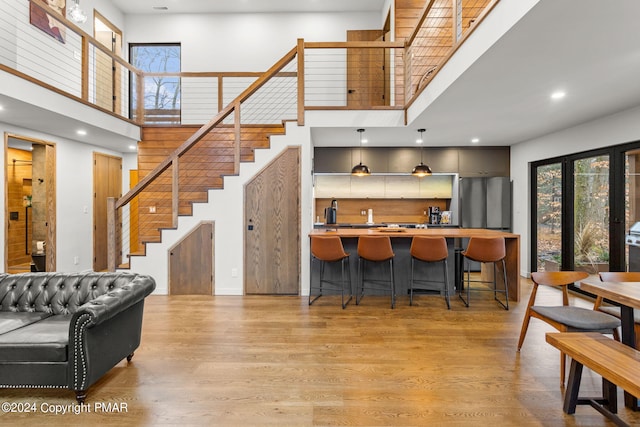 interior space with light wood finished floors, stairway, wet bar, and a high ceiling