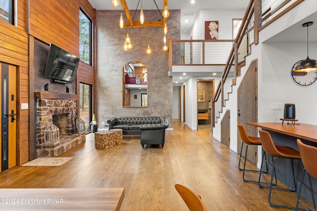 living room featuring visible vents, stairway, a fireplace, a towering ceiling, and wood finished floors