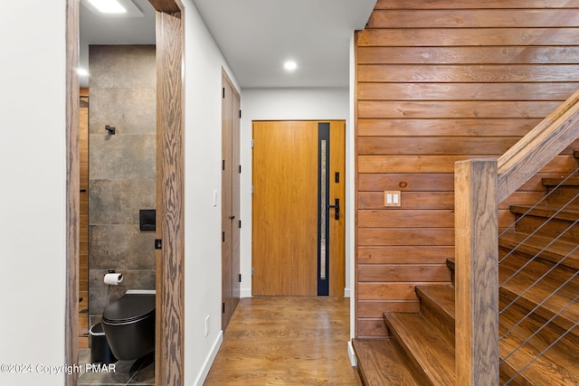 hall with baseboards, wood finished floors, and stairs