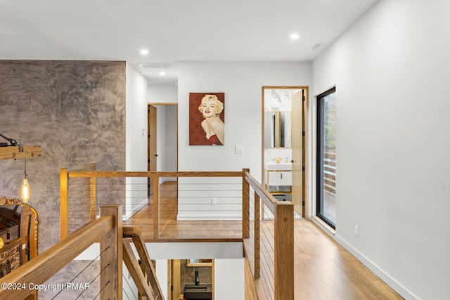 hallway with an upstairs landing, visible vents, recessed lighting, and wood finished floors