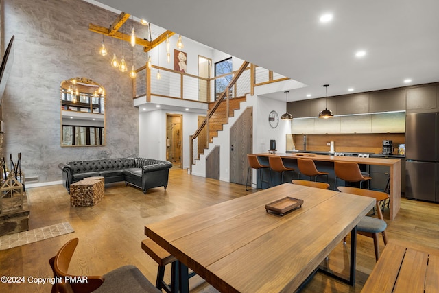 dining room with recessed lighting, stairway, light wood-style floors, and a towering ceiling