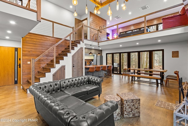 living area featuring visible vents, stairway, a high ceiling, and wood finished floors