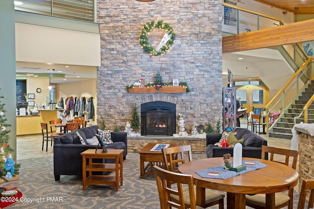 interior space featuring a stone fireplace, stairway, and a towering ceiling