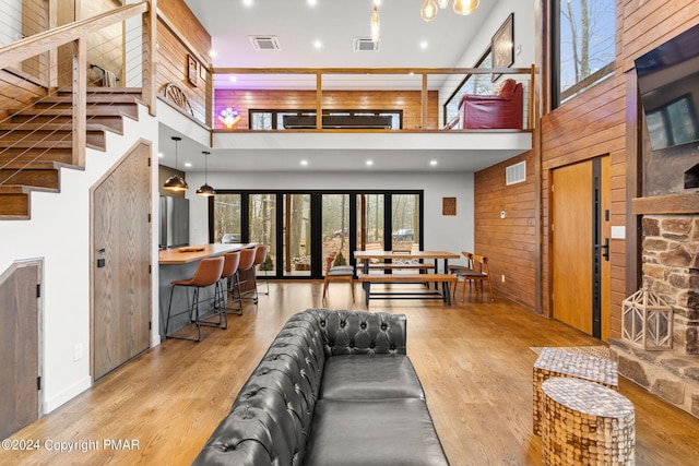 living area with a wealth of natural light, visible vents, wood finished floors, and wood walls