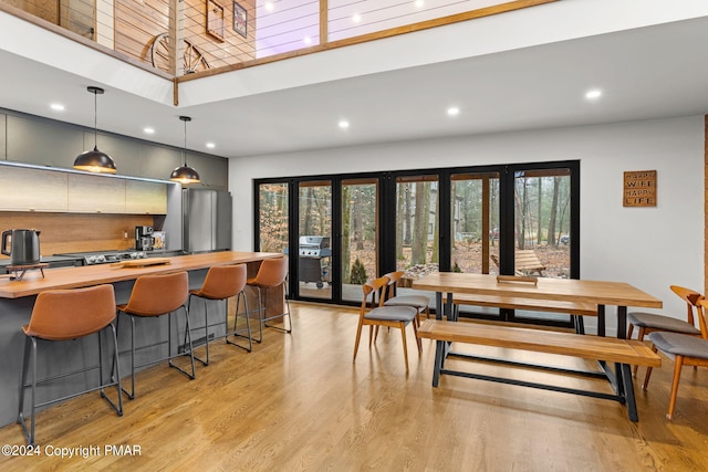 dining room with a wealth of natural light, recessed lighting, light wood-type flooring, and a high ceiling