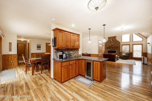 1212 Acacia Dr, Hawley, PA 18428 - kitchen with radiator, wine cooler, a wainscoted wall, a stone fireplace, and brown cabinetry