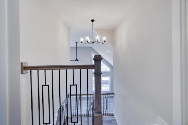 stairway with baseboards, high vaulted ceiling, wood finished floors, and ceiling fan with notable chandelier