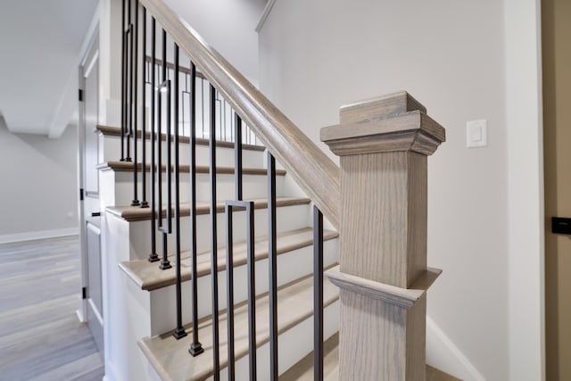 staircase featuring wood finished floors and baseboards