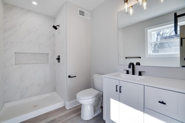 bathroom featuring visible vents, toilet, wood finished floors, a shower stall, and vanity