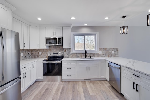 kitchen featuring backsplash, light wood-style flooring, stainless steel appliances, white cabinetry, and a sink