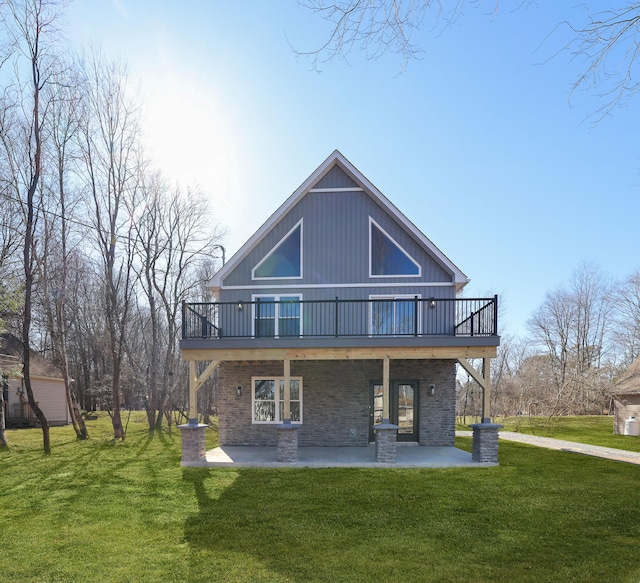 back of house featuring brick siding, a deck, a lawn, and a patio