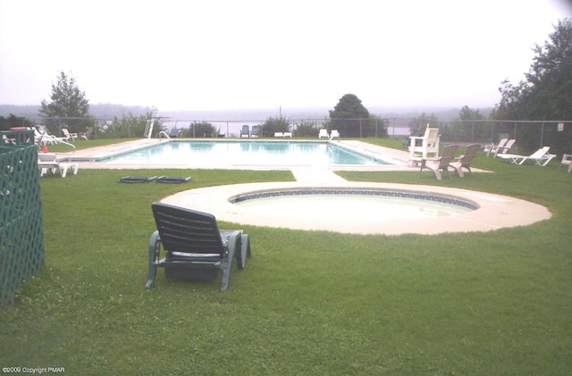 community pool featuring a patio area, a lawn, and fence