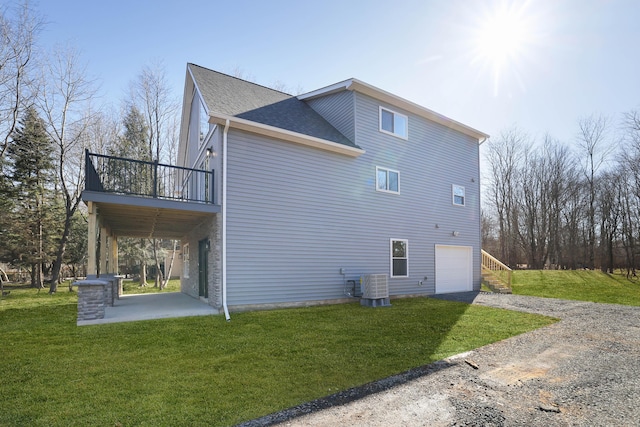 view of home's exterior featuring central air condition unit, a garage, driveway, and a yard