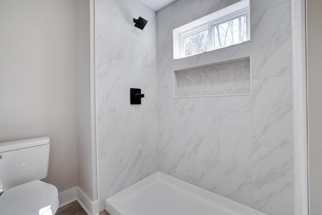 bathroom featuring a shower, baseboards, and toilet