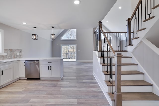 kitchen featuring decorative light fixtures, dishwasher, light countertops, light wood-style flooring, and white cabinets