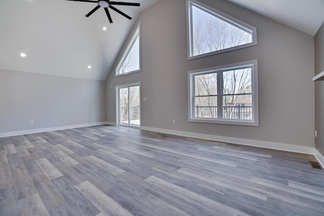 unfurnished living room with baseboards, high vaulted ceiling, wood finished floors, and a ceiling fan