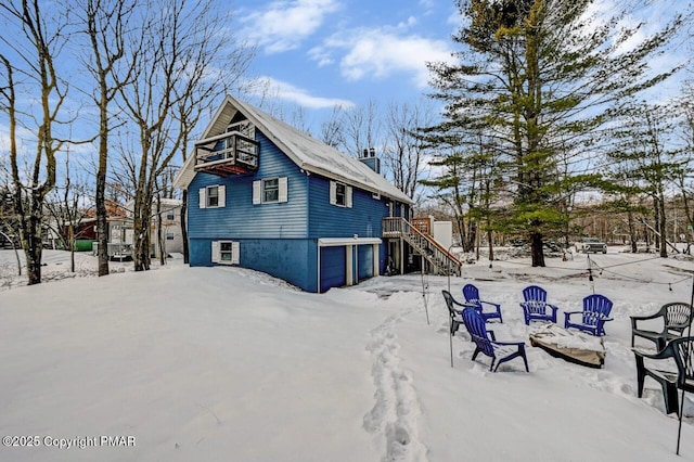 snow covered rear of property featuring a garage