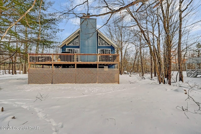 snow covered house with a deck and a chimney