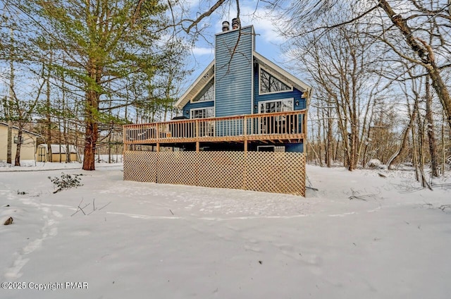 snow covered rear of property featuring a wooden deck