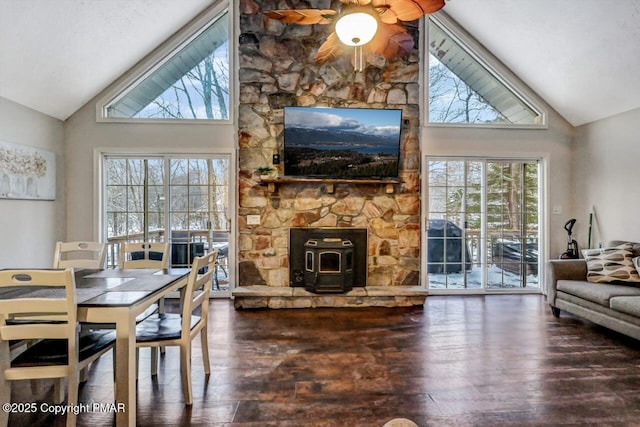 dining space featuring ceiling fan, dark hardwood / wood-style floors, a wood stove, and high vaulted ceiling