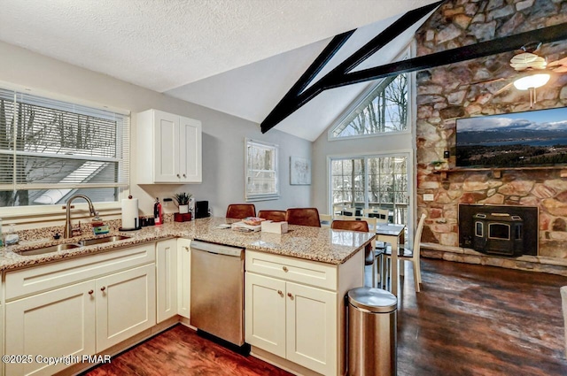 kitchen with sink, vaulted ceiling, dishwasher, kitchen peninsula, and light stone countertops