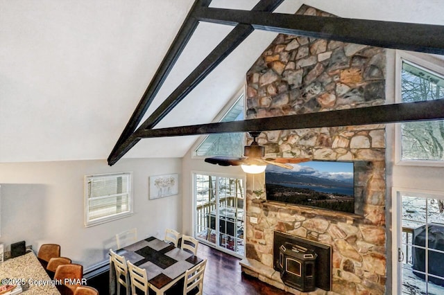 living room with ceiling fan, hardwood / wood-style floors, a wood stove, and vaulted ceiling with beams