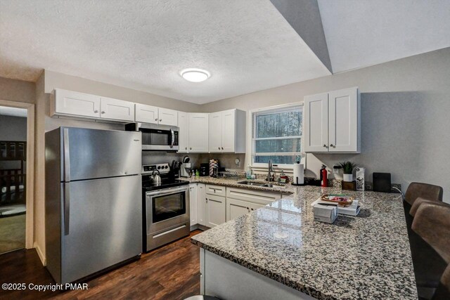 kitchen featuring light stone counters, appliances with stainless steel finishes, sink, and white cabinets